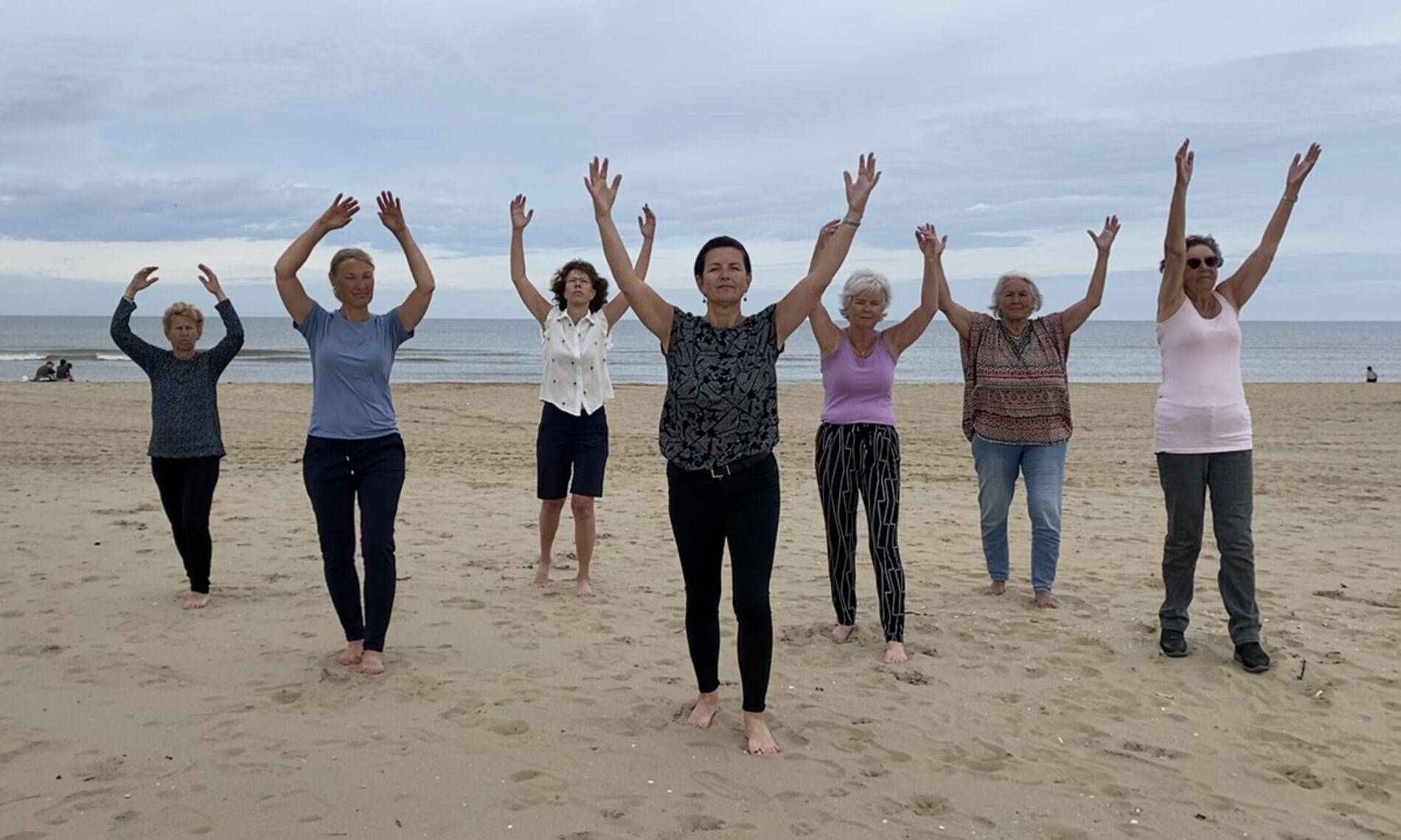 Groep op het strand met de armen omhoog